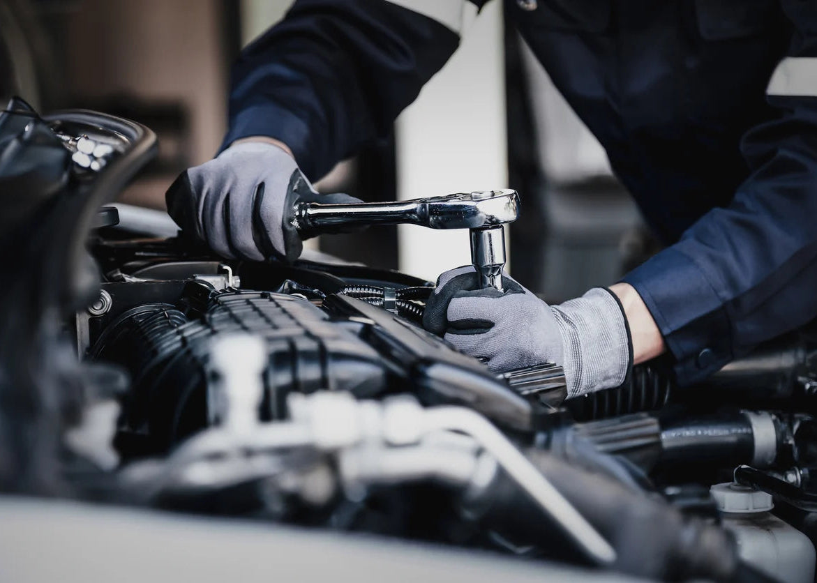 Mechanic working on a car engine with tools